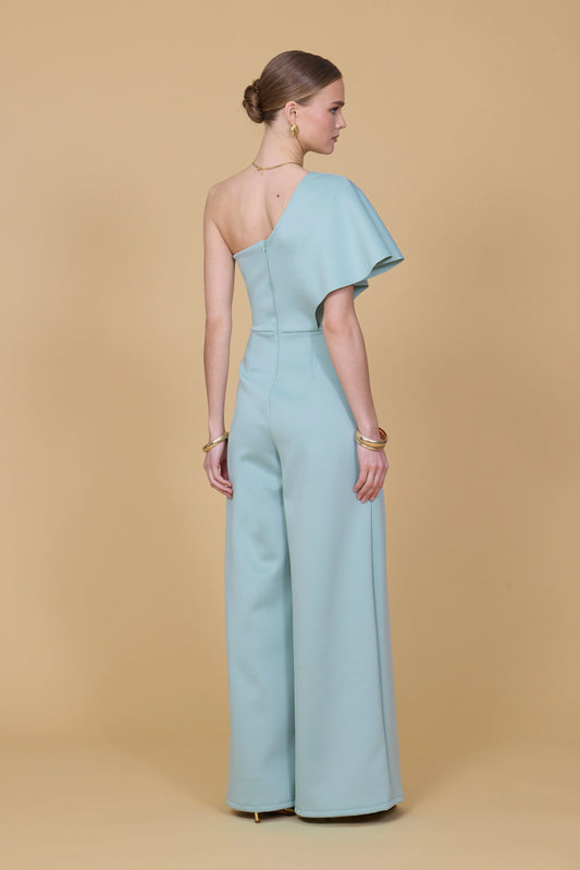 Woman wearing a light blue one-shoulder jumpsuit on a beige background