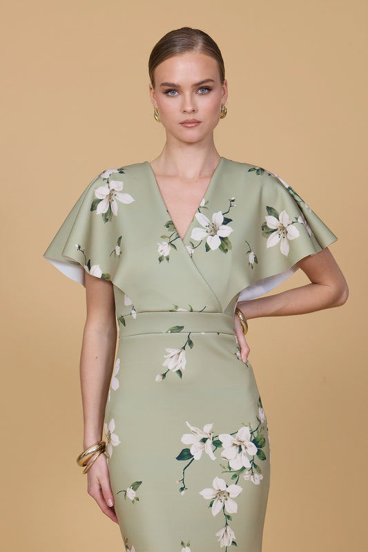 Woman wearing a green floral dress against a beige background