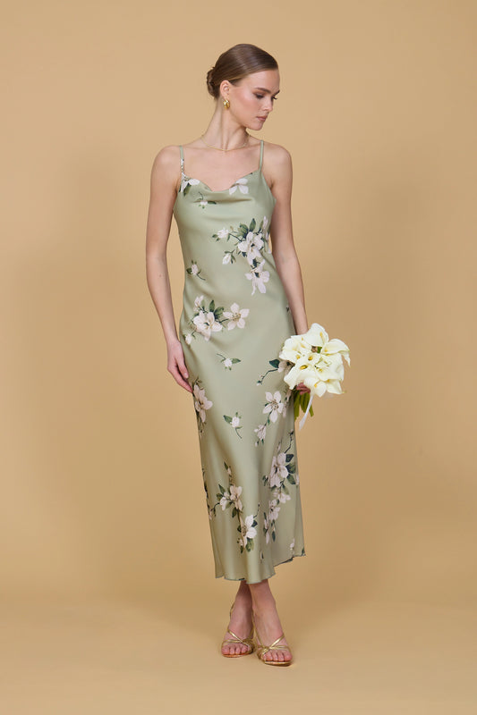 Woman wearing a floral dress holding flowers against a beige background
