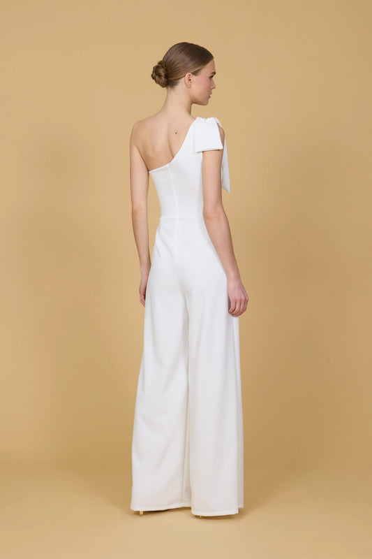 Woman wearing a white one-shoulder jumpsuit against a beige background
