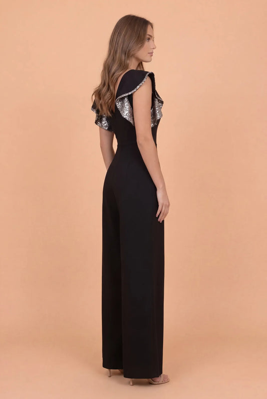 Woman wearing a black dress with ruffled sleeves on a peach background