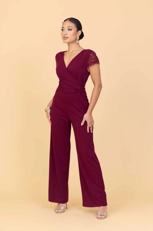 Woman wearing a burgundy jumpsuit on a beige background
