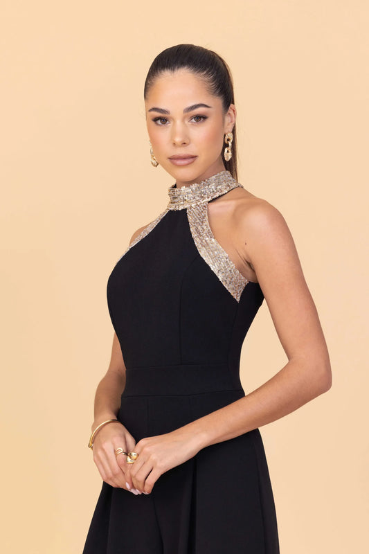 Woman wearing a black dress with a beaded neckline on a beige background
