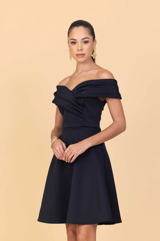 Woman wearing a black off-shoulder dress against a beige background