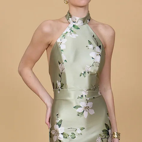 Woman wearing a light green floral dress against a beige background