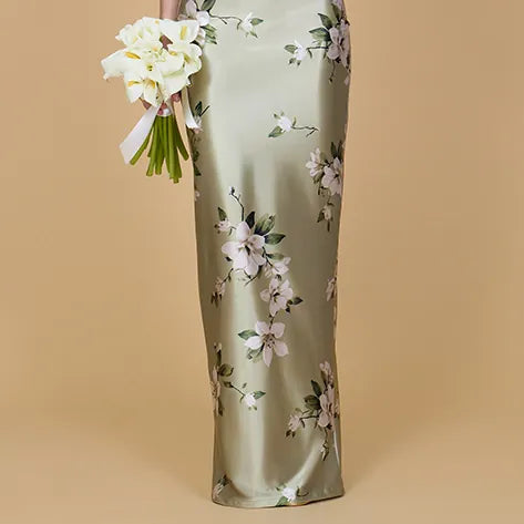 Woman wearing a floral dress holding a bouquet against a beige background