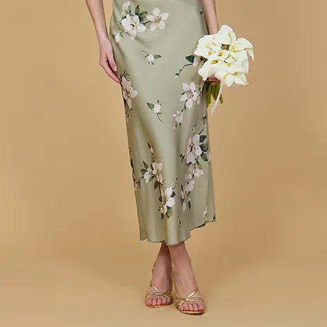 Woman wearing a floral dress holding white flowers against a beige background