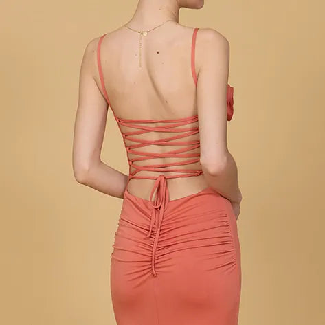 Coral dress with thin straps and open back on a beige background