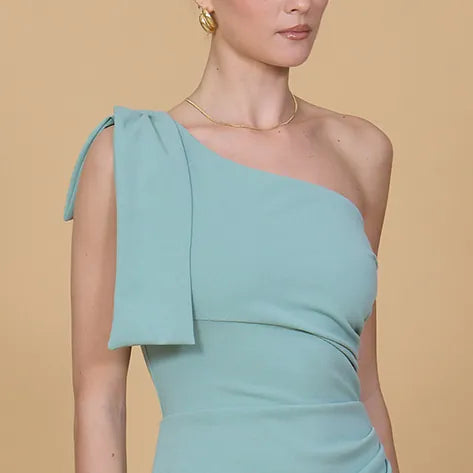 Woman wearing a light blue one-shoulder dress against a beige background