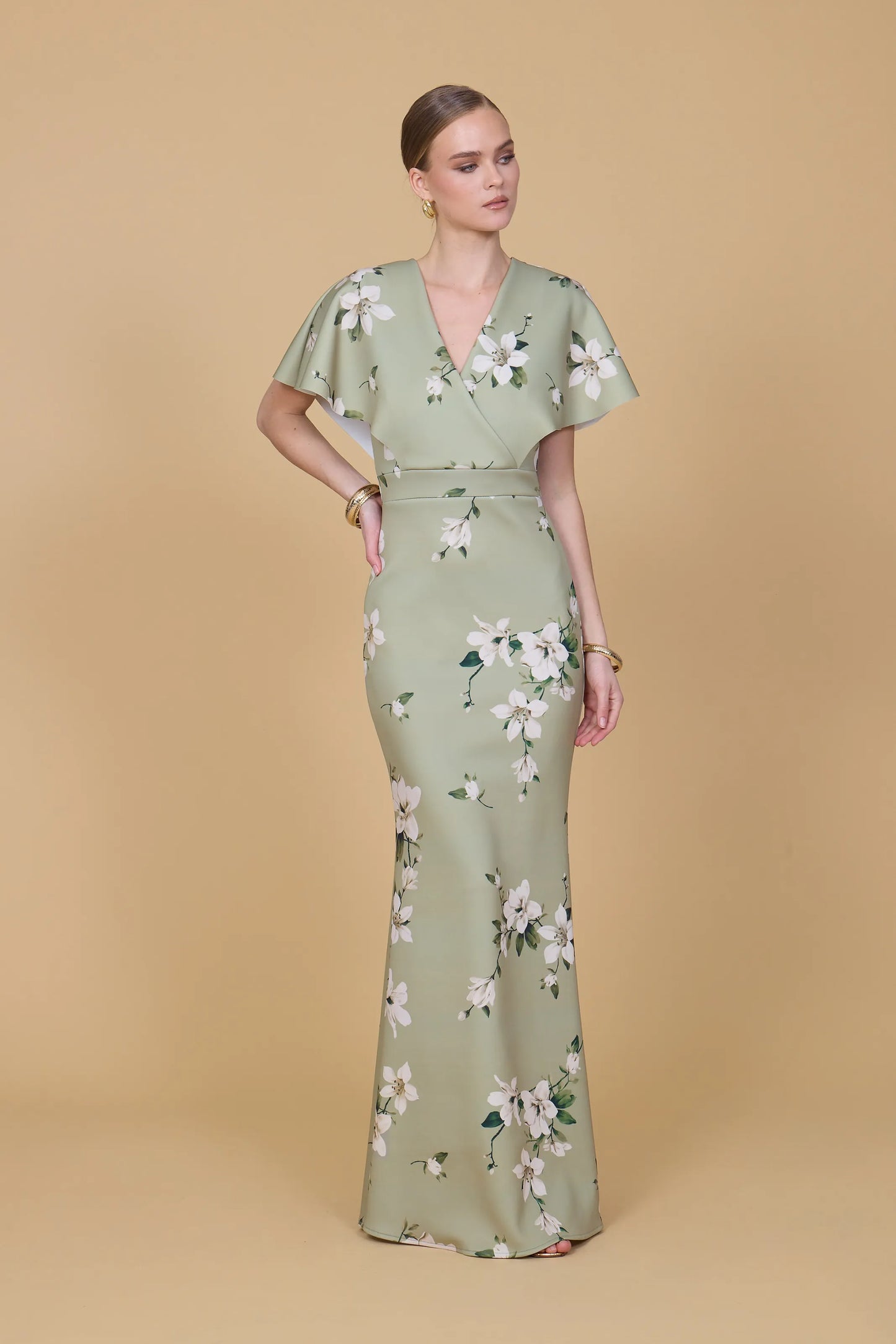 Woman wearing a green floral dress against a beige background