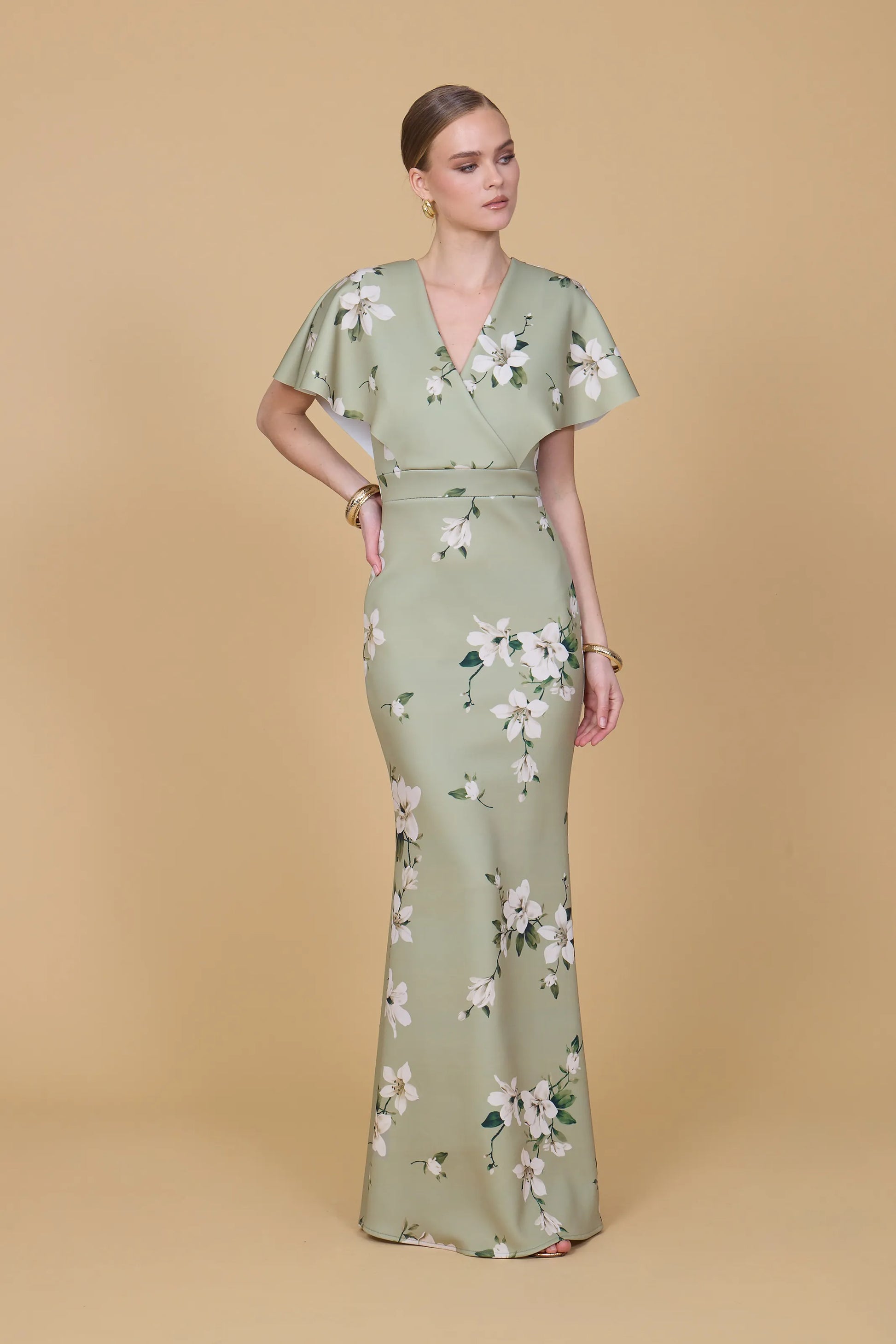 Woman wearing a green floral dress against a beige background