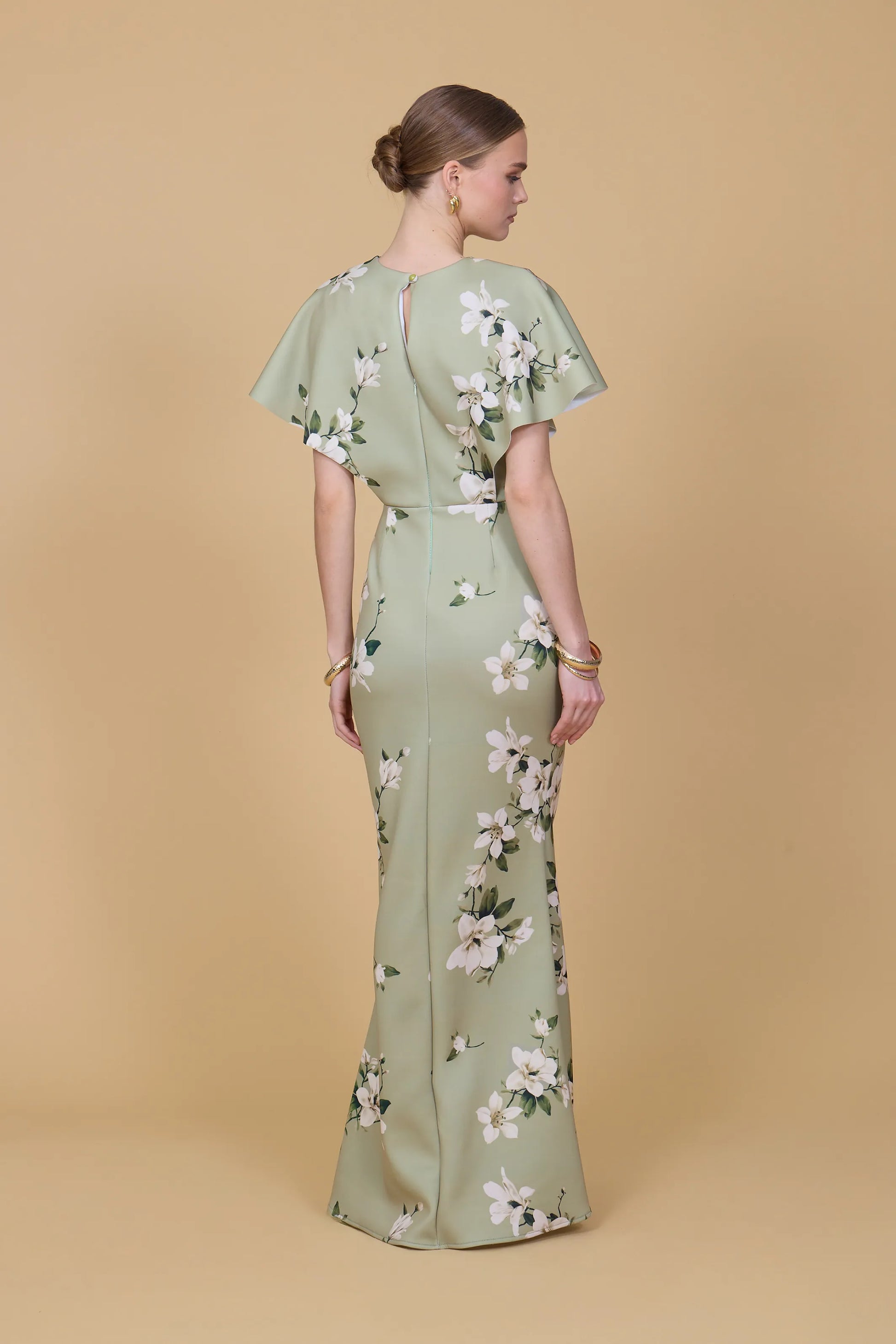 Woman wearing a green floral dress against a beige background