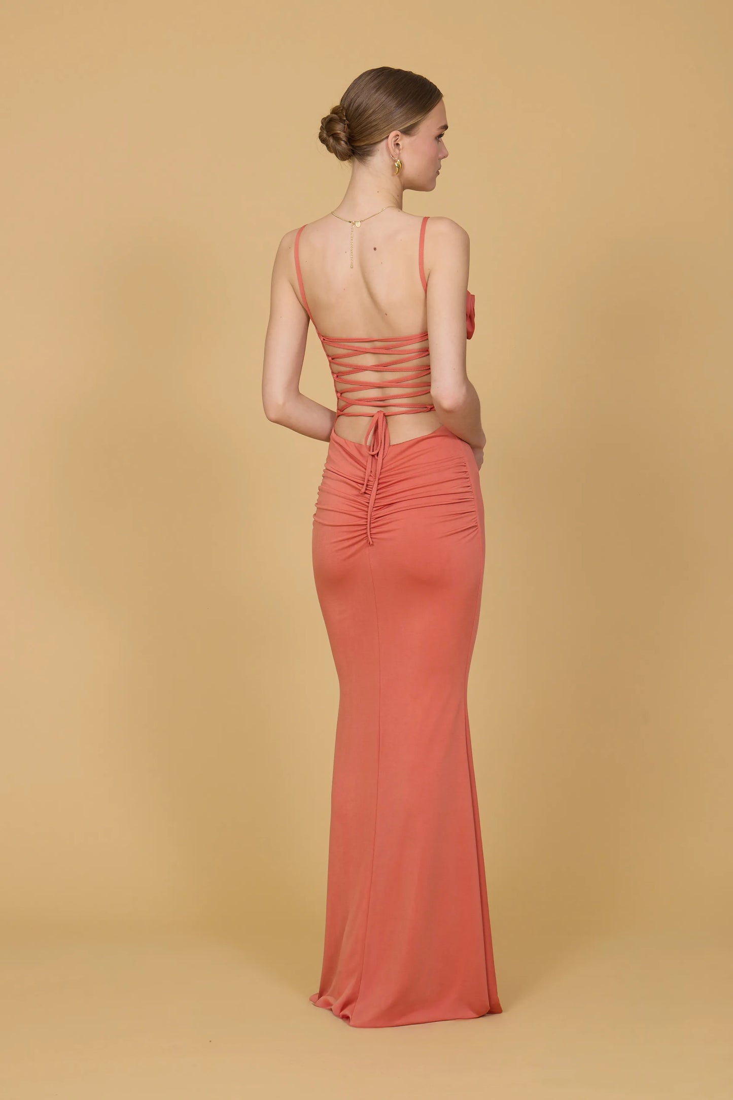 Woman wearing a coral evening gown against a beige background