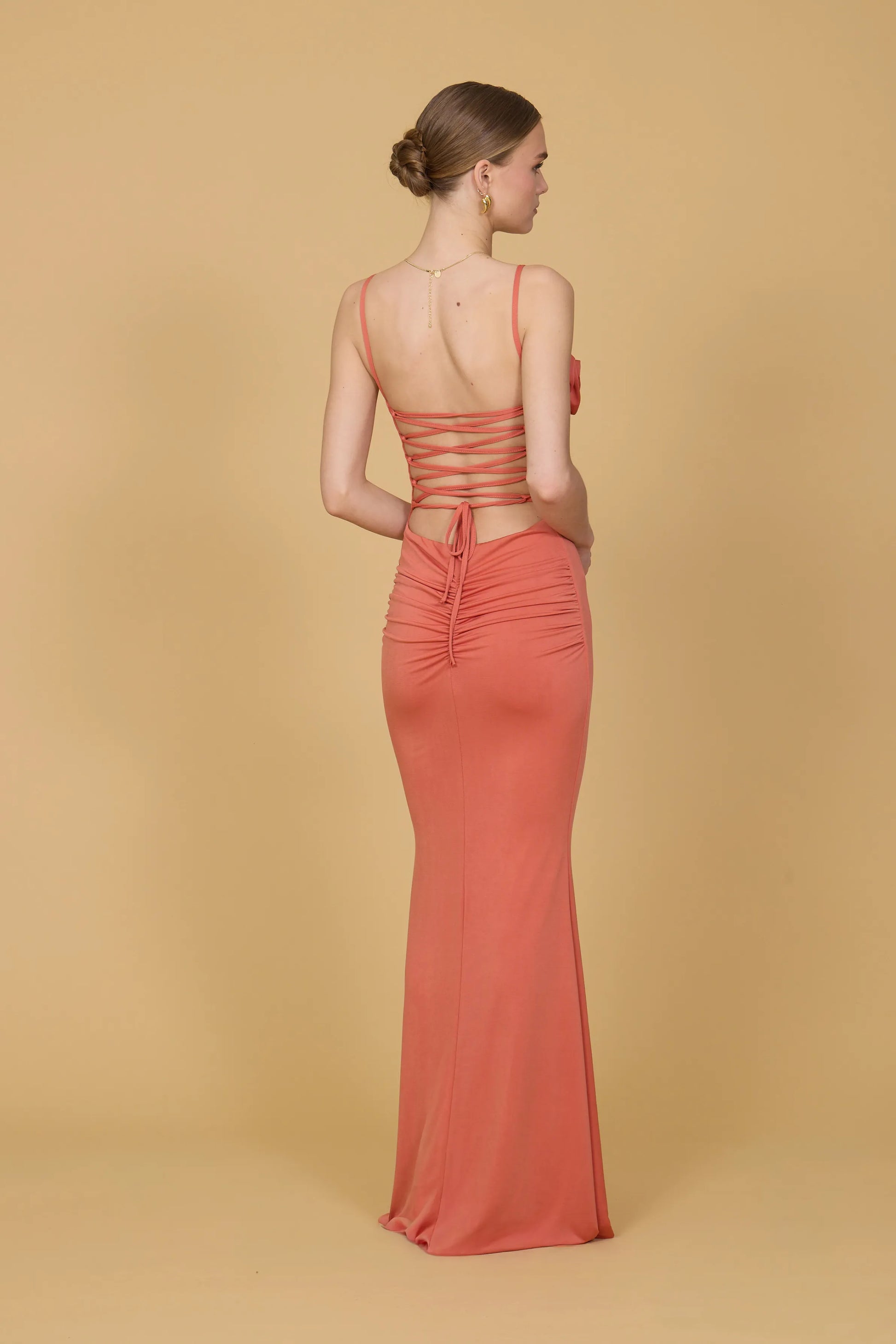 Woman wearing a coral evening gown against a beige background