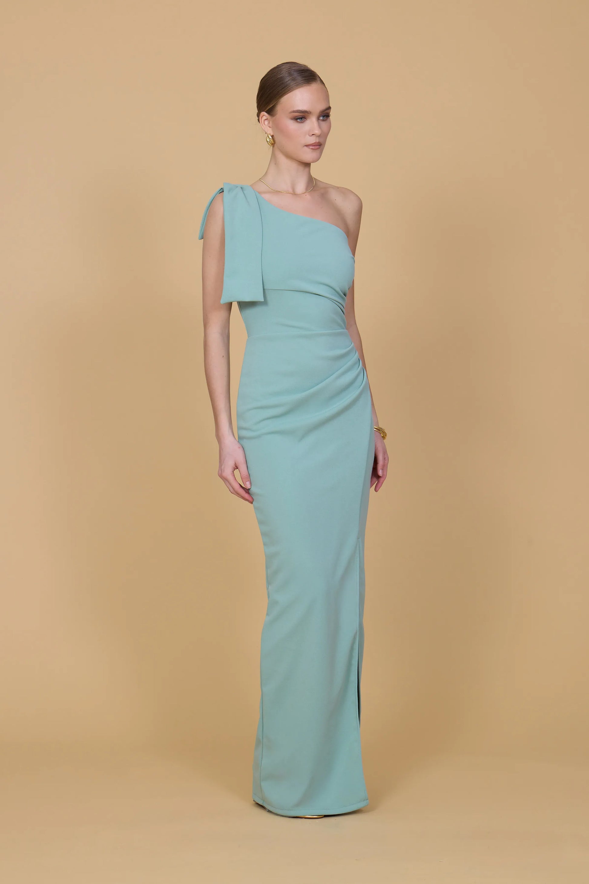 Woman wearing a light blue one-shoulder dress against a beige background
