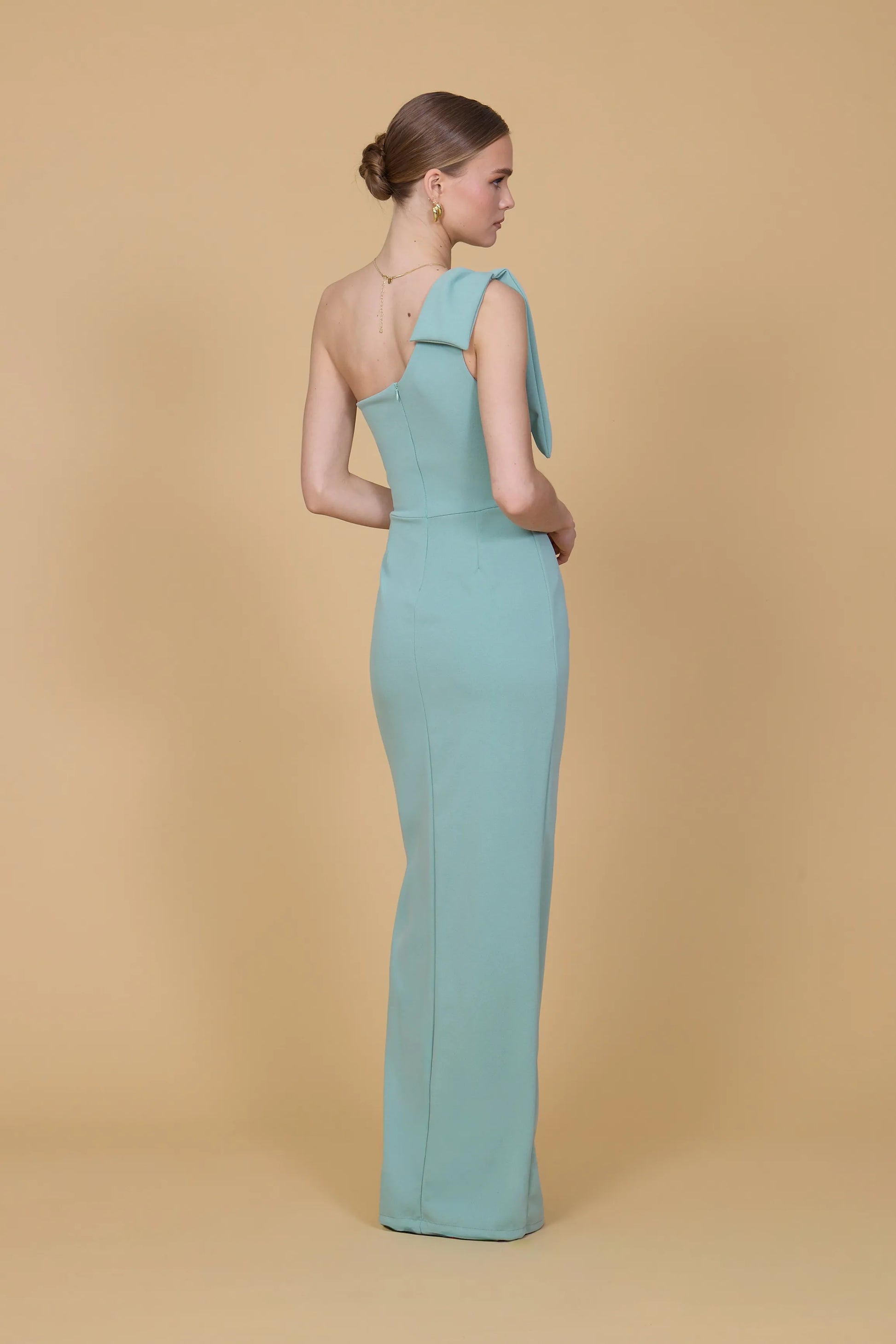 Woman wearing a light blue gown against a beige background
