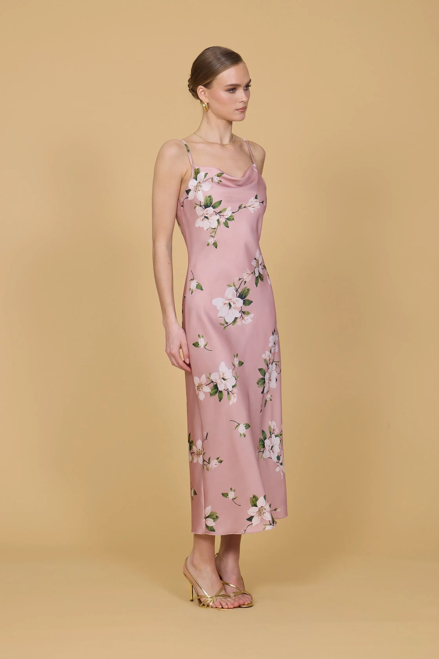 Woman wearing a pink floral dress against a beige background