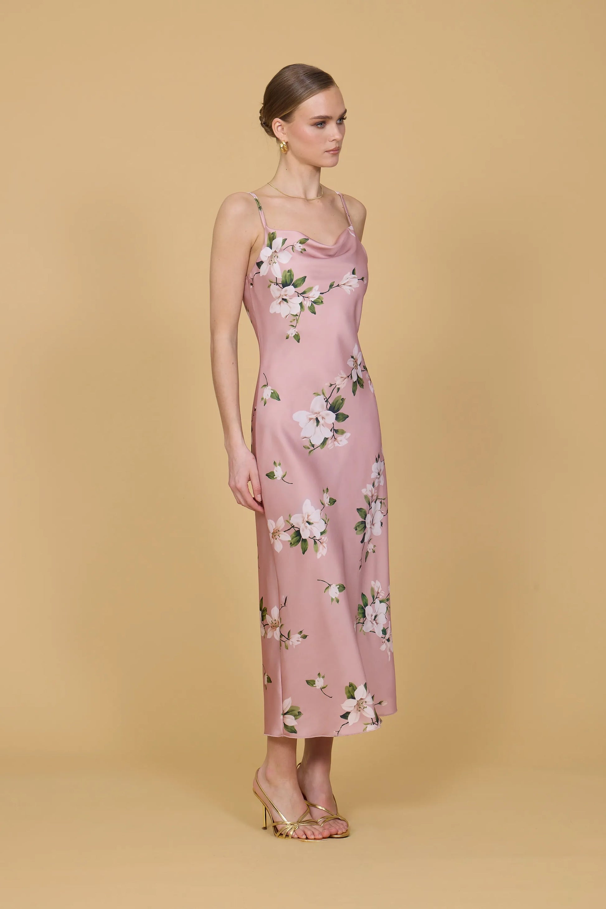 Woman wearing a pink floral dress against a beige background