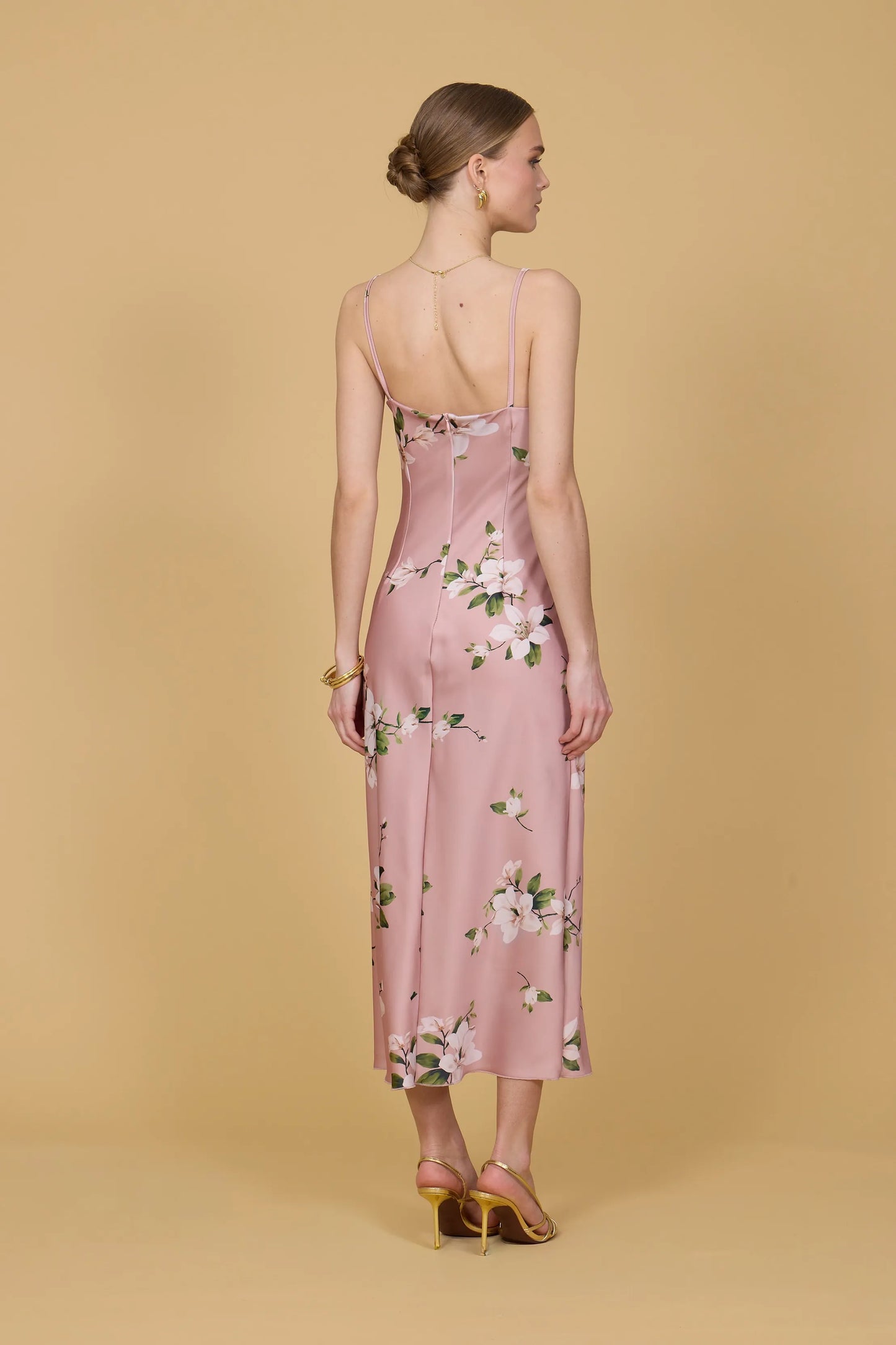 Woman wearing a pink floral dress against a beige background