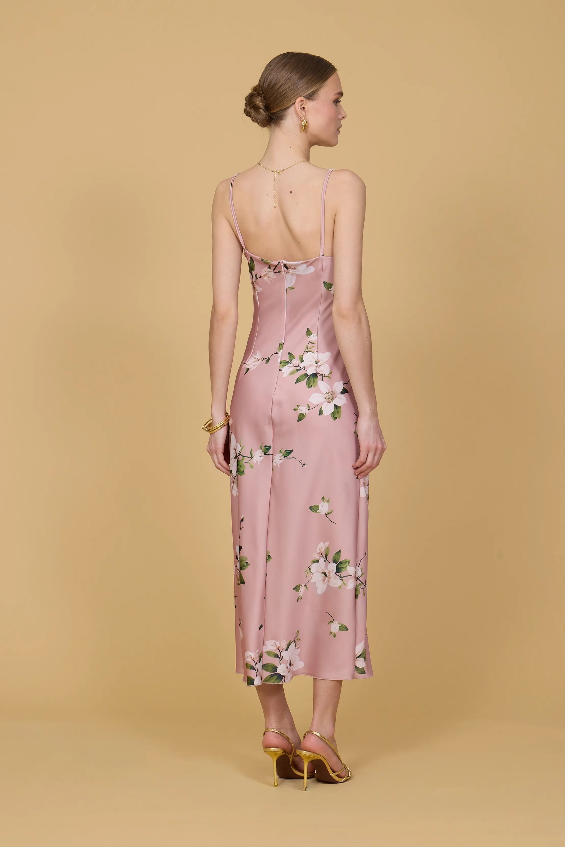 Woman wearing a pink floral dress against a beige background
