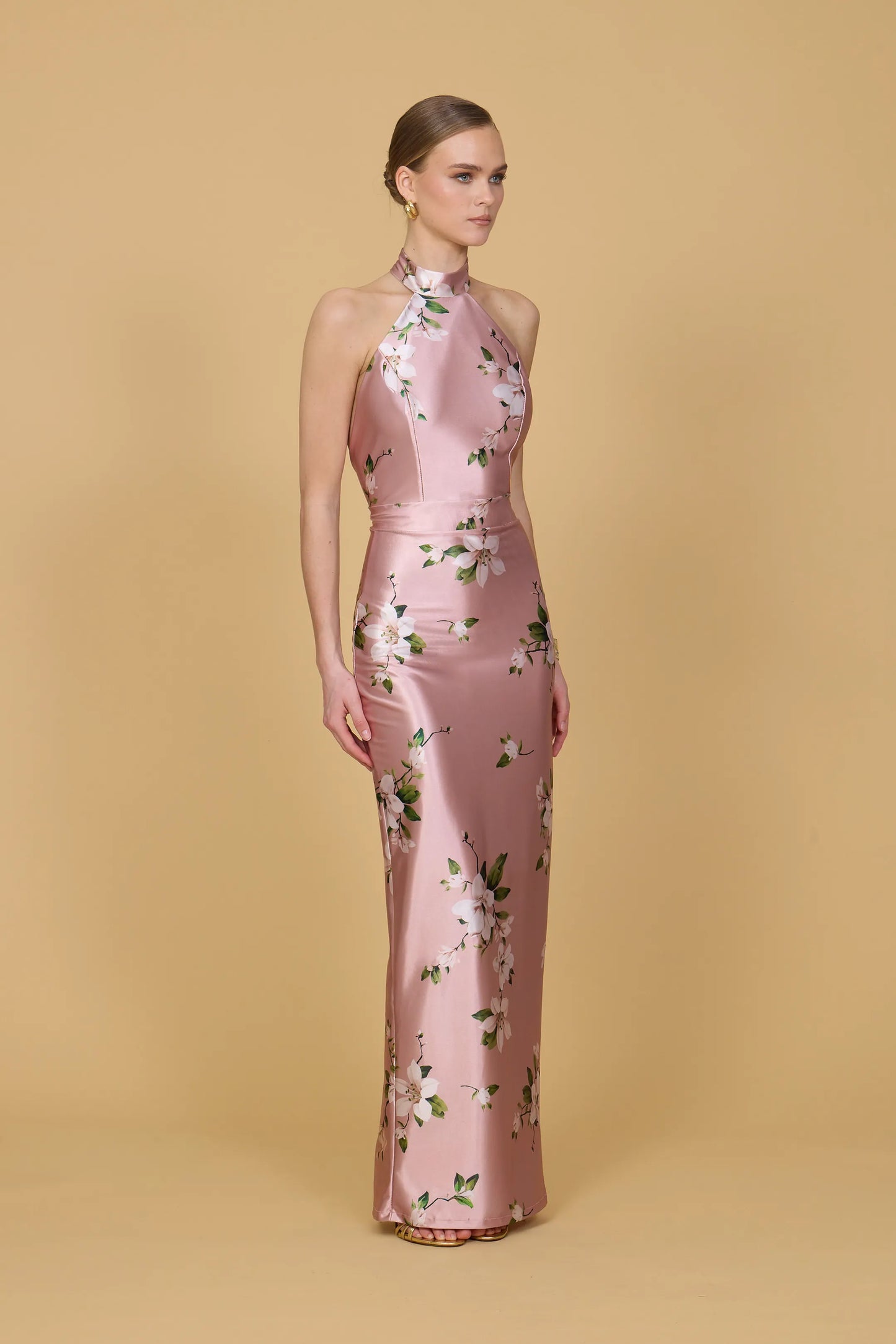 Woman wearing a pink floral dress against a beige background