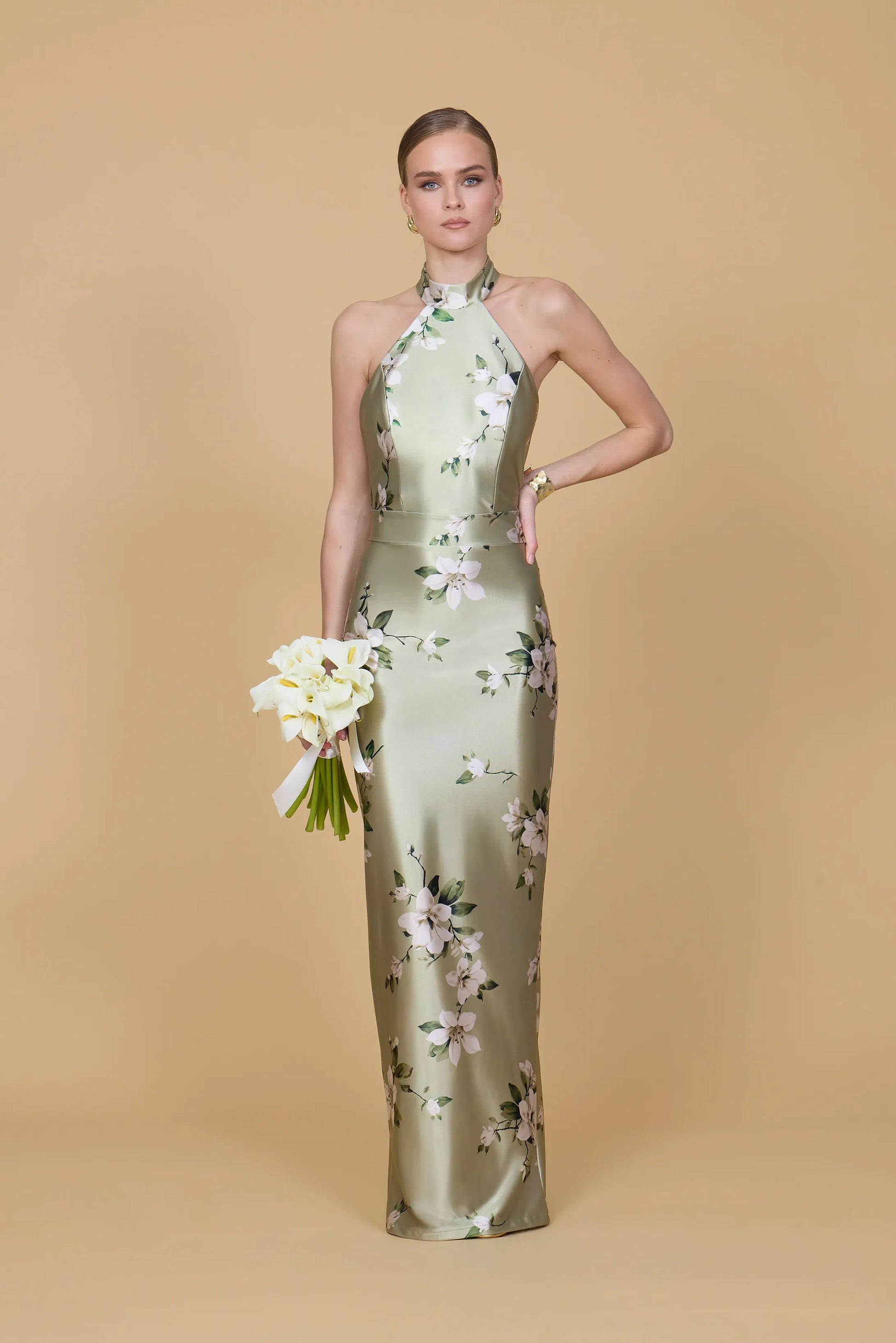 Woman wearing a green floral dress against a beige background