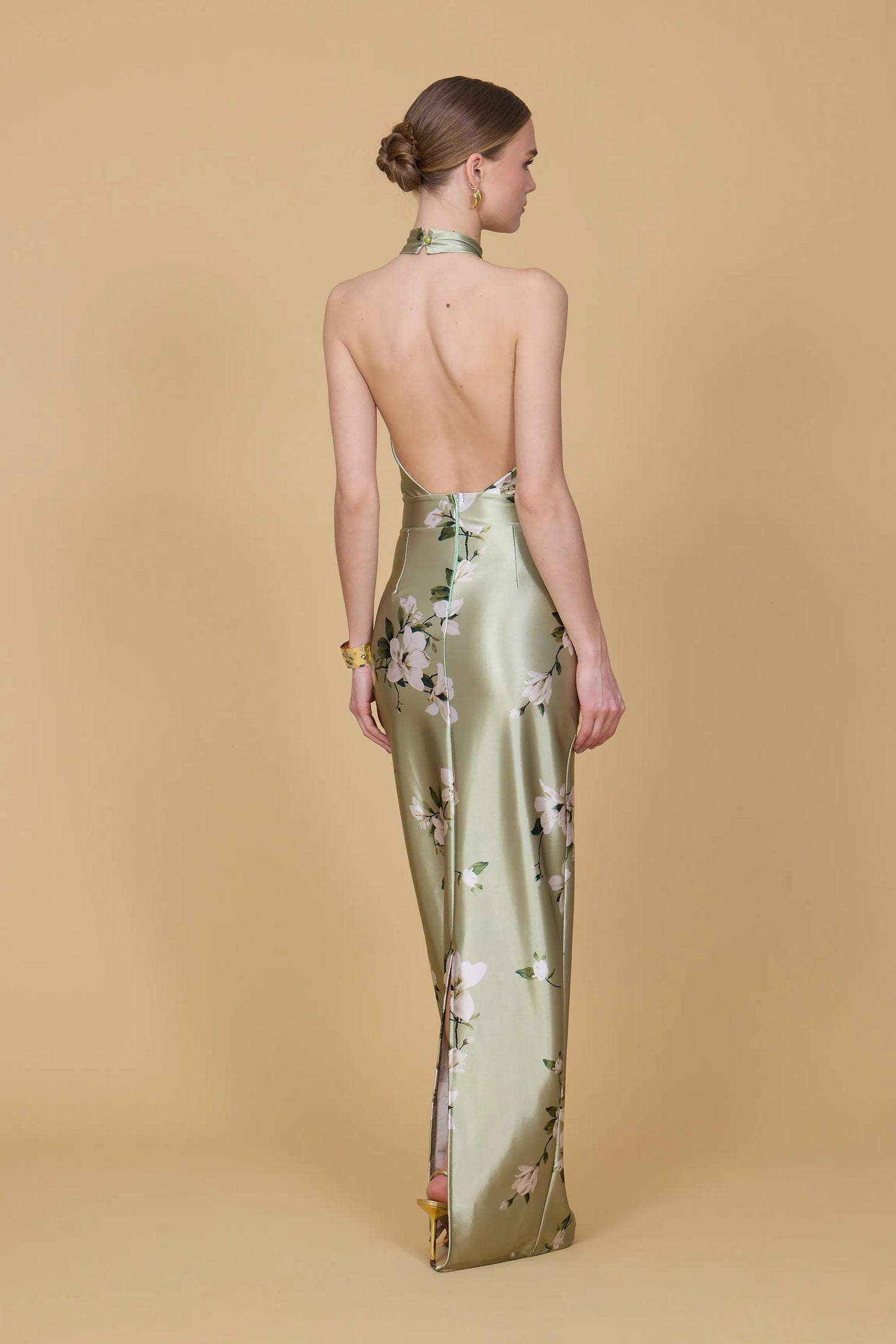 Woman wearing a floral evening gown with an open back on a beige background
