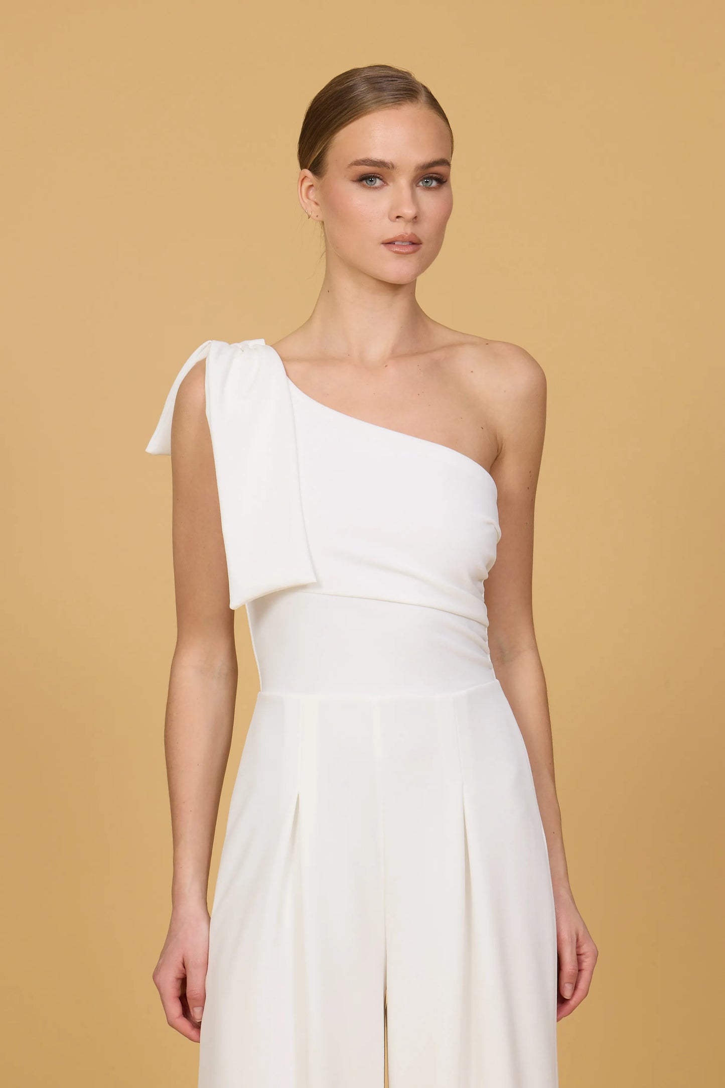 Woman wearing a white one-shoulder dress against a beige background