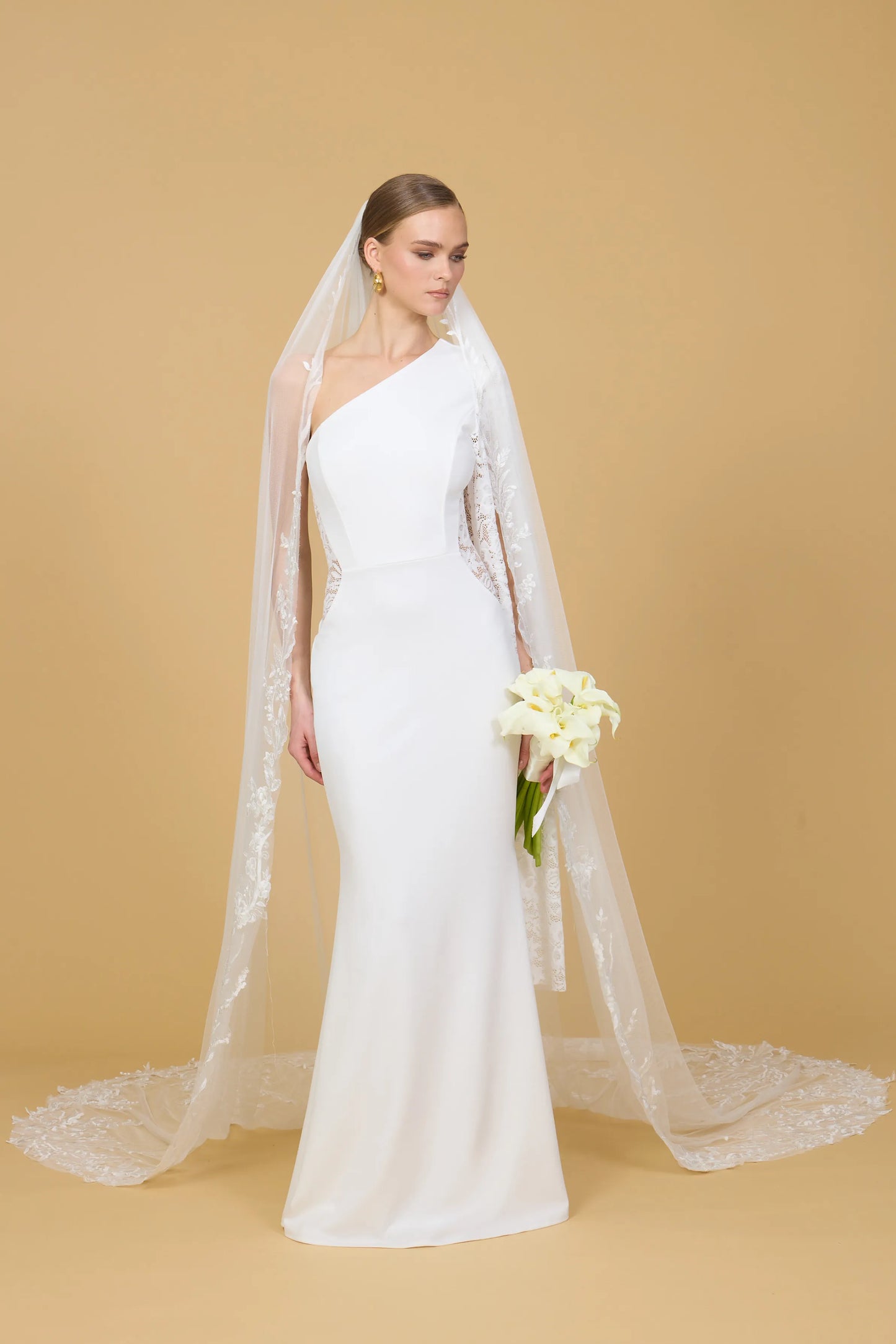 Woman wearing a white one-shoulder dress against a beige background