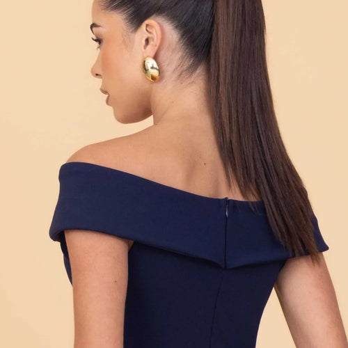 Woman wearing a navy off-shoulder dress with a beige background