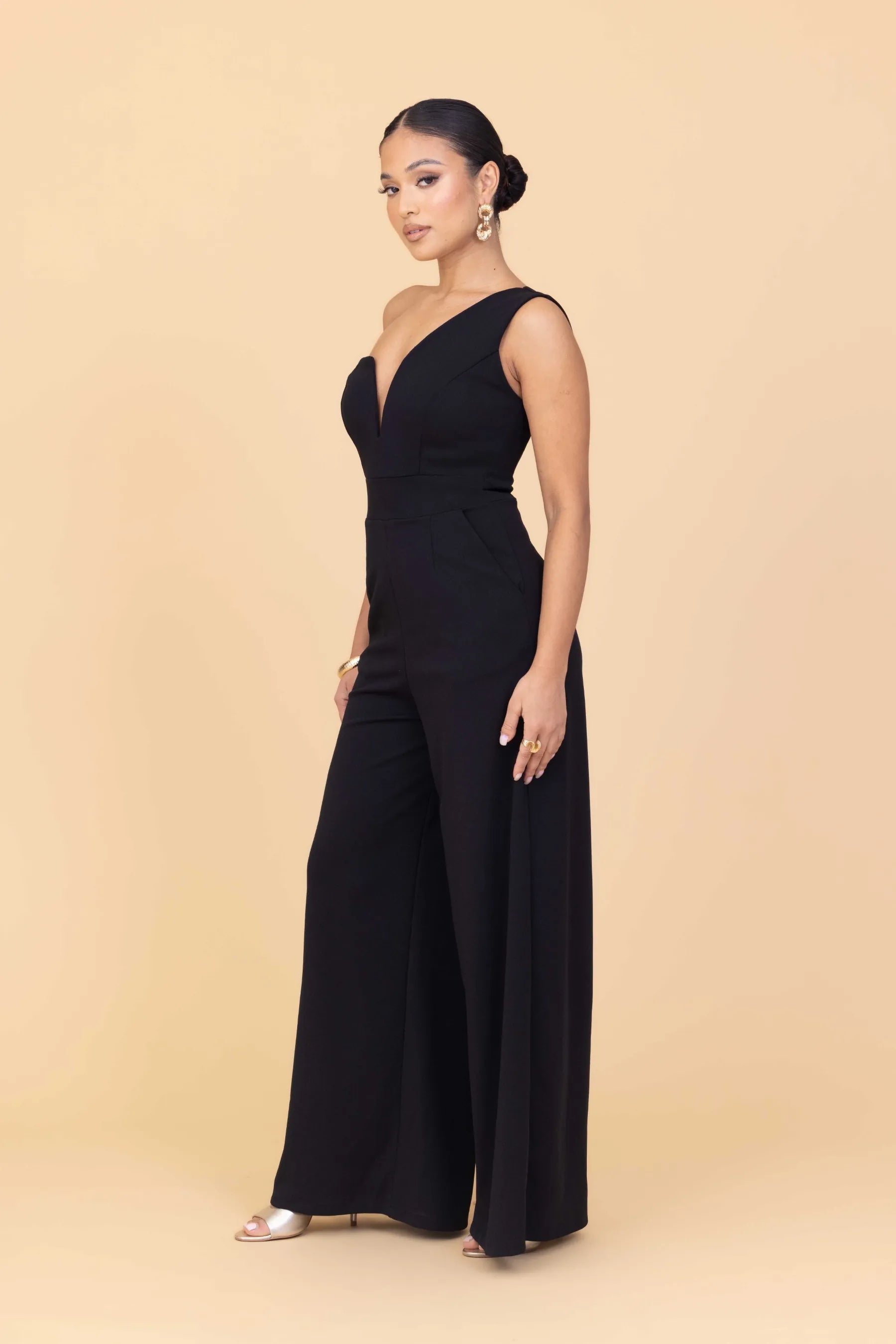 Woman wearing a black jumpsuit on a beige background