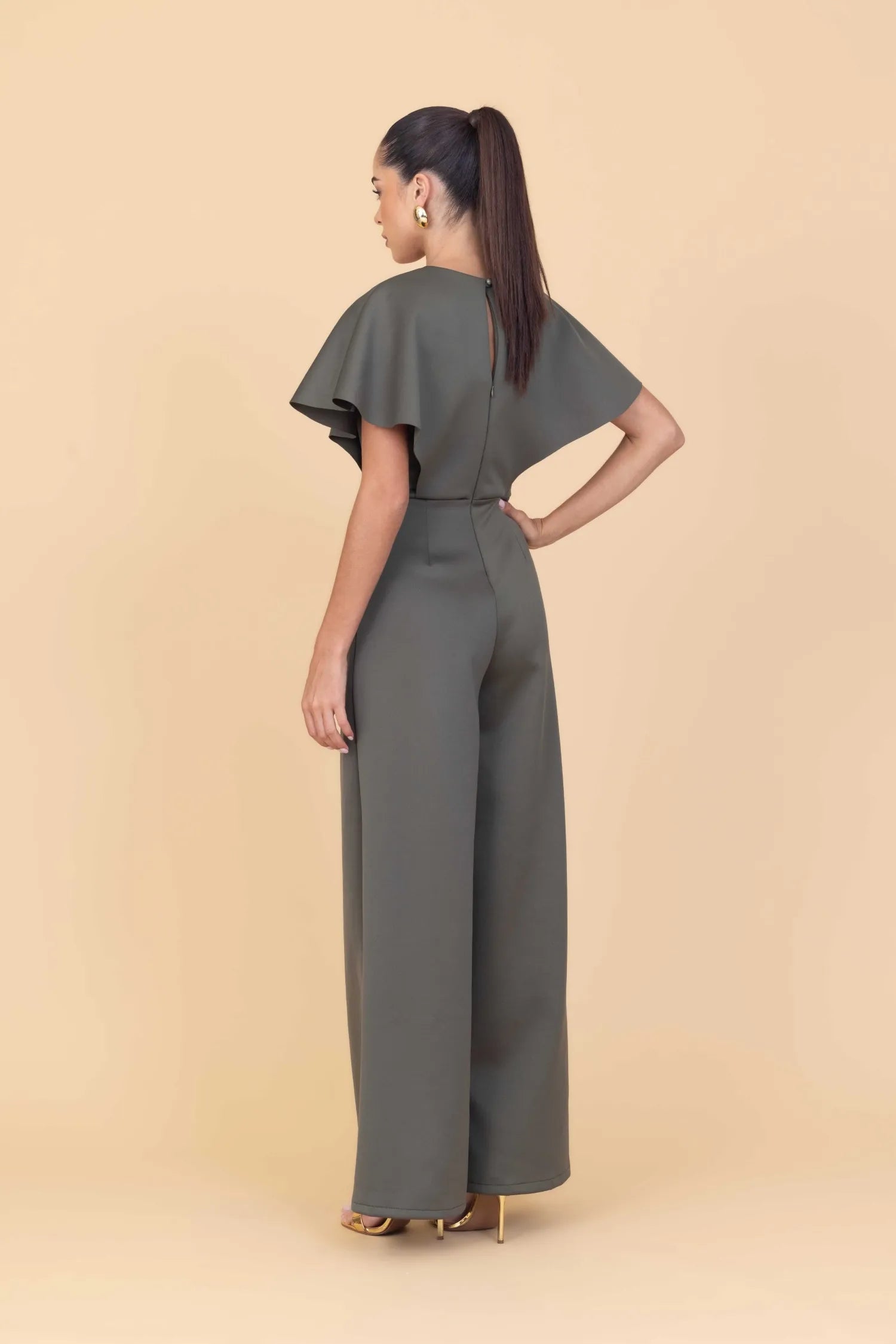 Woman wearing a gray jumpsuit on a beige background