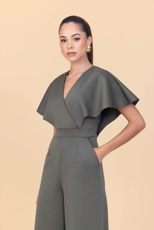 Woman wearing a gray jumpsuit against a beige background