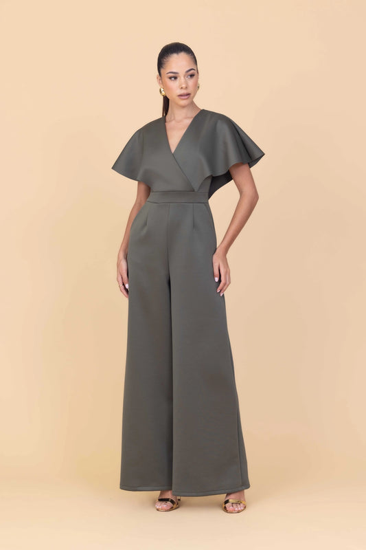 Woman wearing a green jumpsuit on a beige background