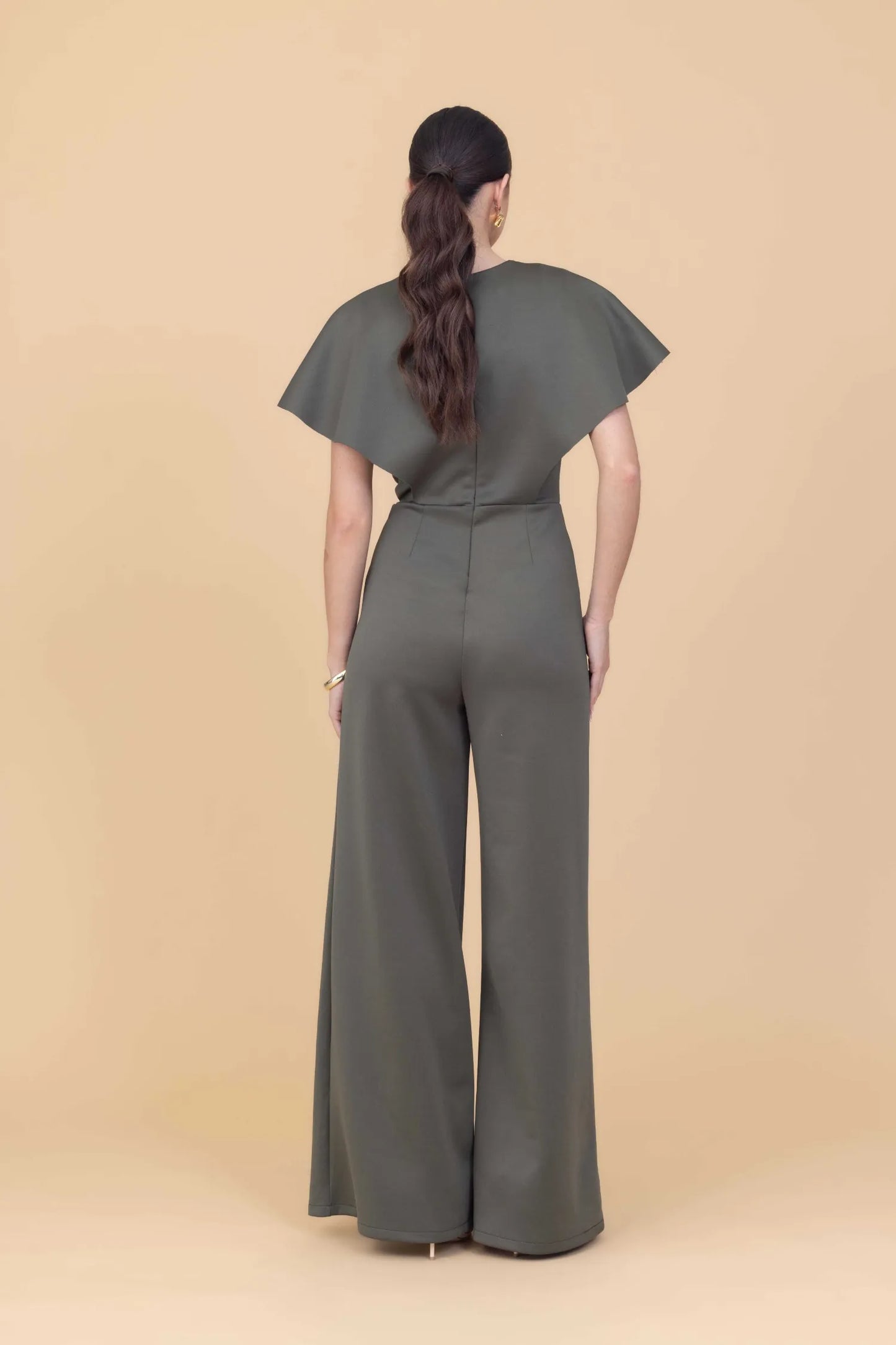 Person wearing a green jumpsuit on a beige background