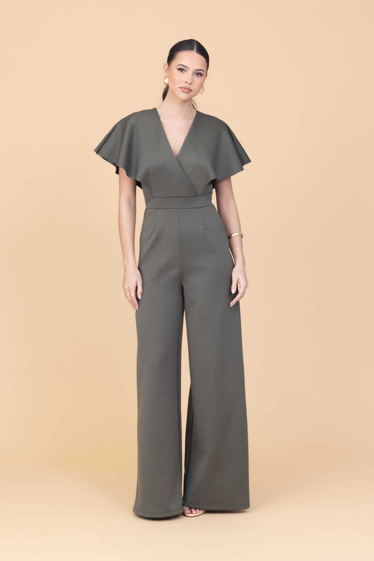 Woman wearing a green jumpsuit against a beige background