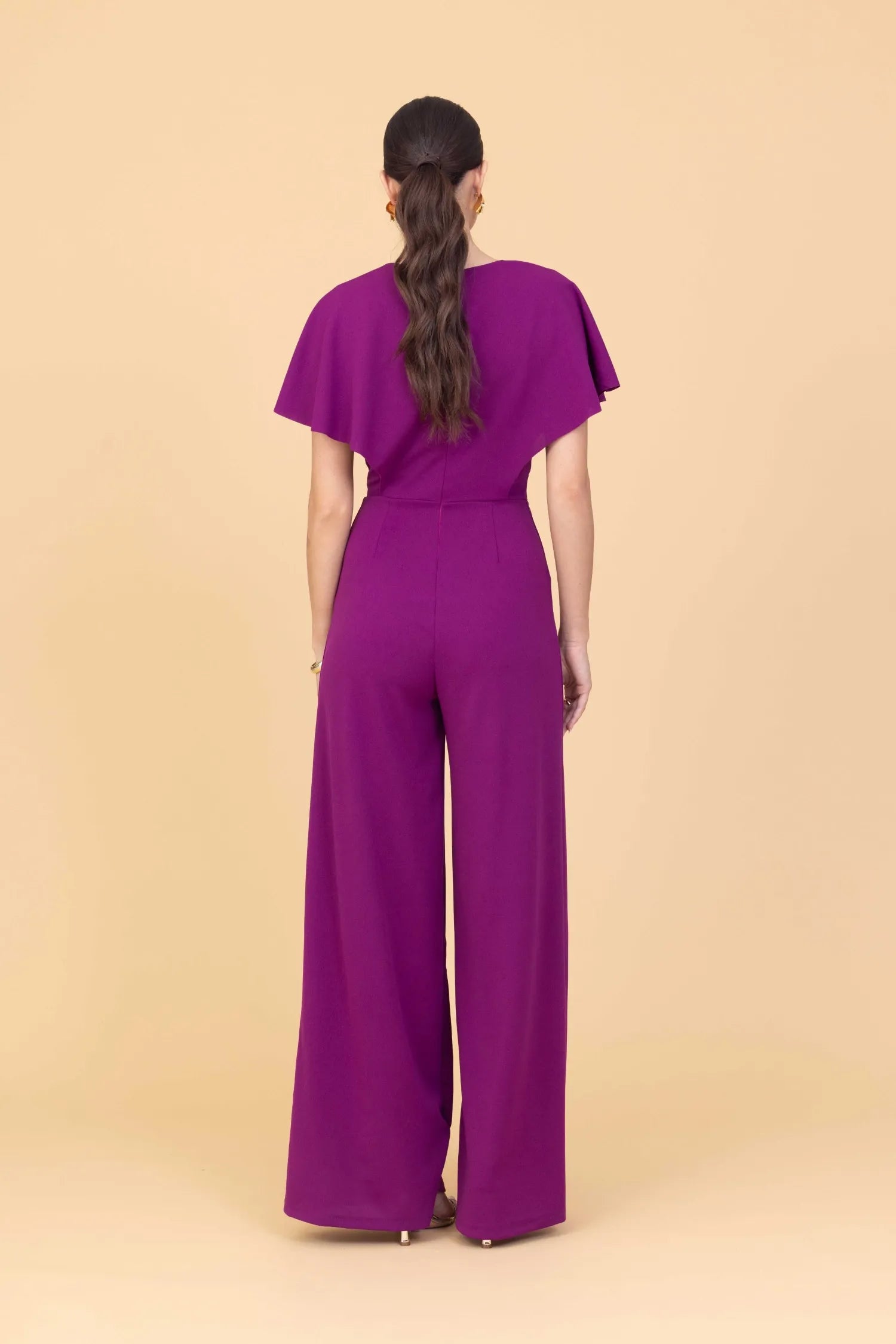 Person wearing a purple jumpsuit on a beige background