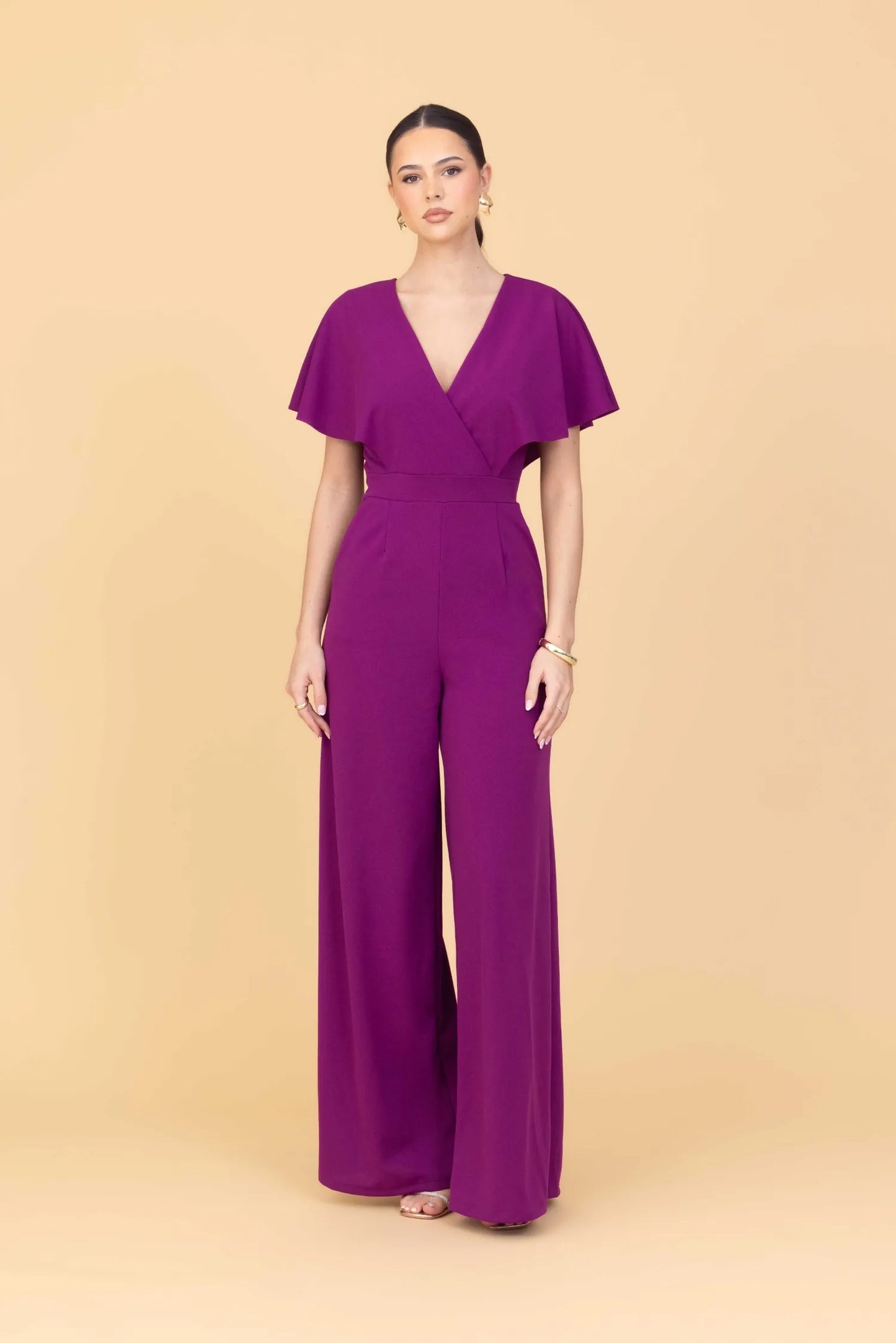 Woman wearing a purple jumpsuit on a beige background