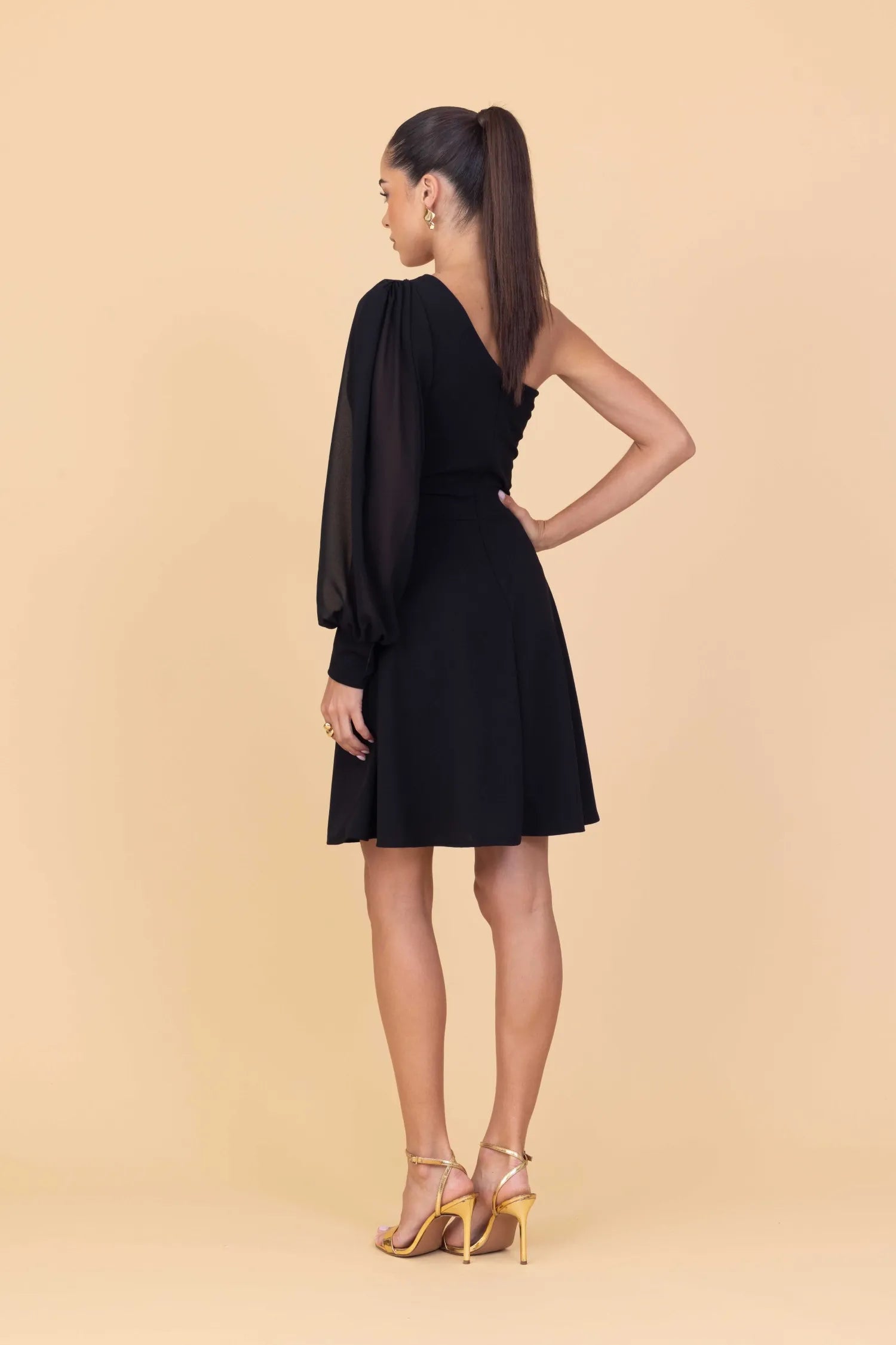 Woman wearing a black one-shoulder dress on a beige background