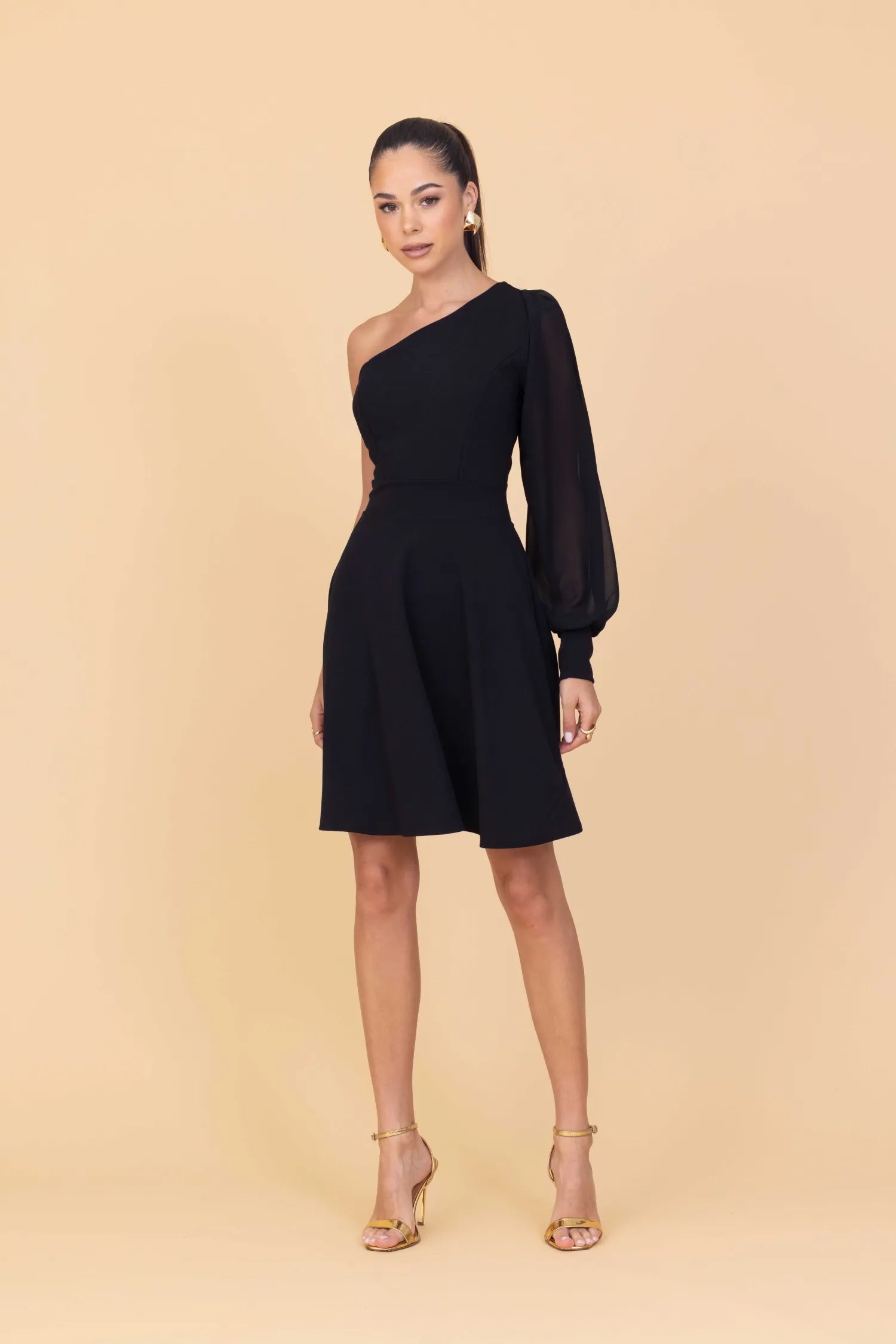 Woman wearing a black one-shoulder dress on a beige background