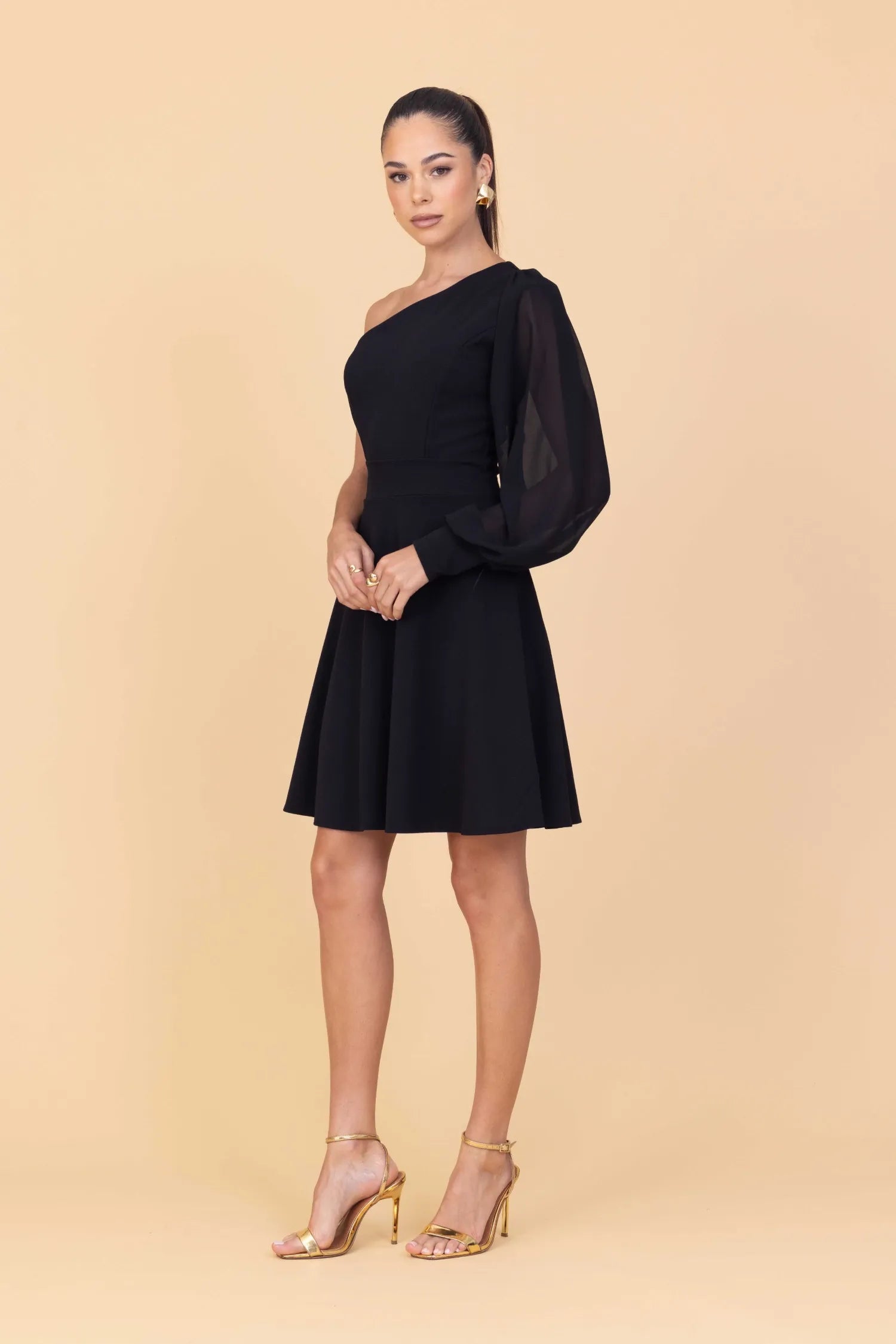 Woman wearing a black one-shoulder dress on a beige background
