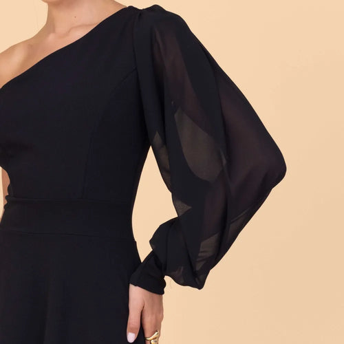 Black one-shoulder dress with sheer sleeves on a beige background