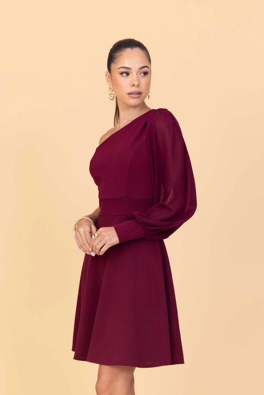 Woman wearing a burgundy one-shoulder dress against a beige background