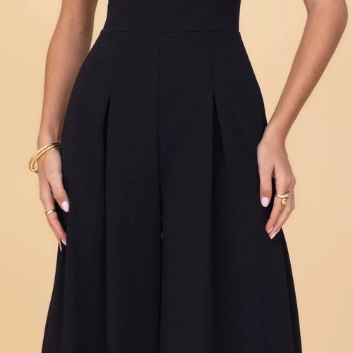 Black dress worn by a person on a beige background