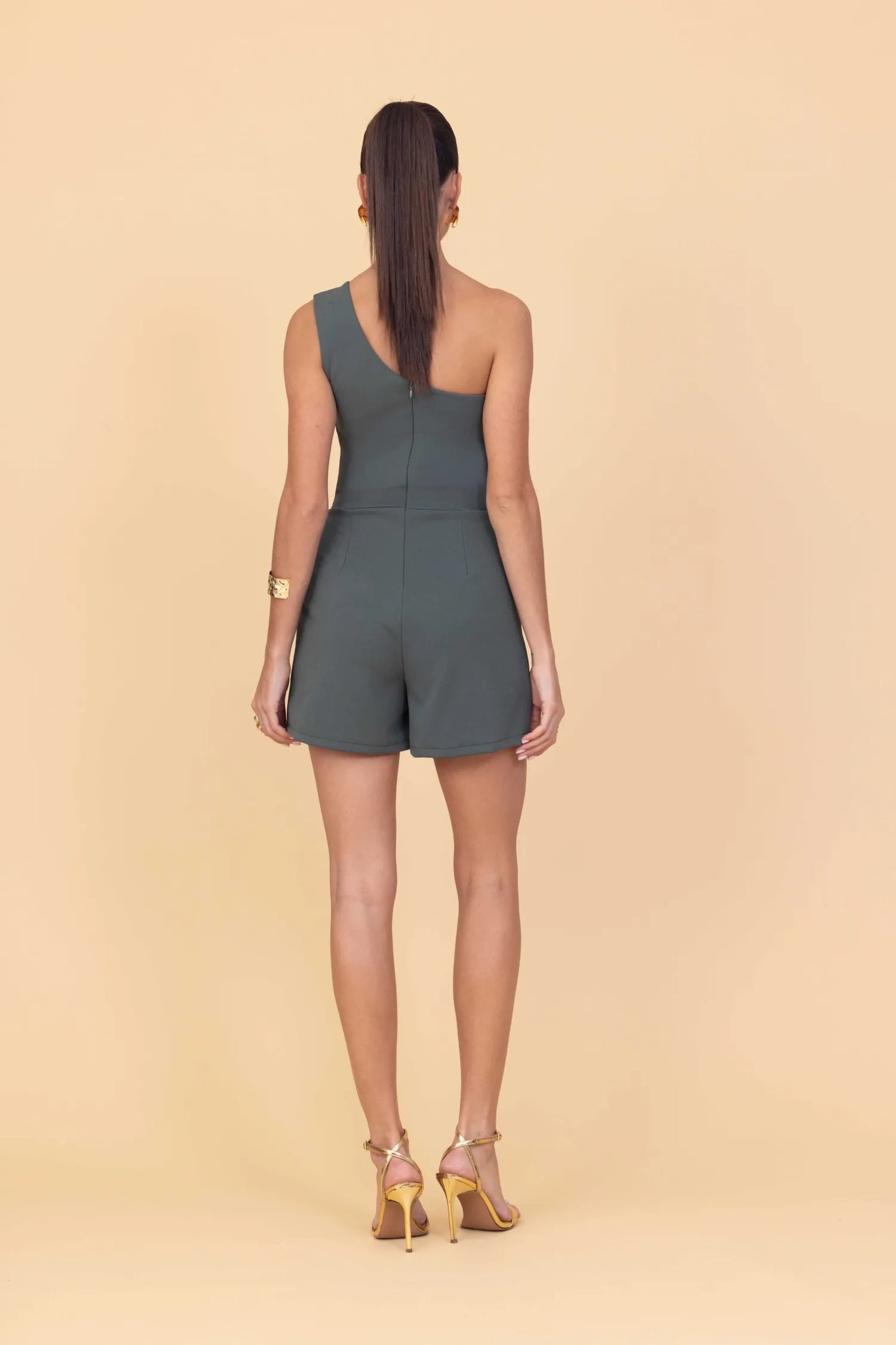 Woman wearing a green romper on a beige background