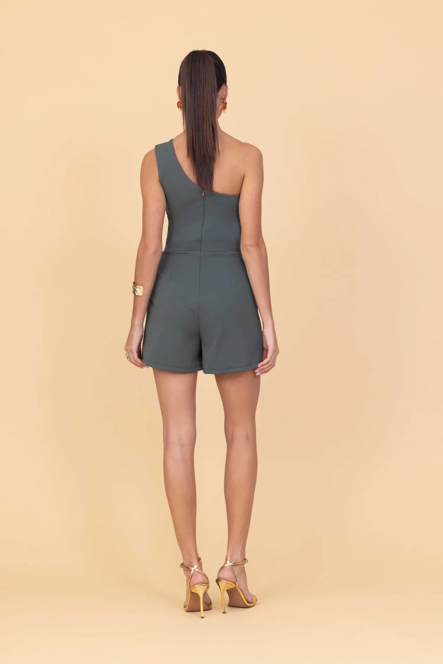 Woman wearing a green romper on a beige background