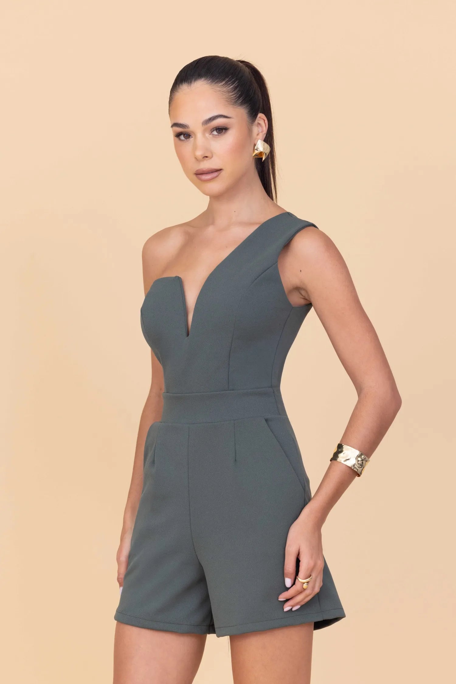 Woman wearing a green romper against a beige background