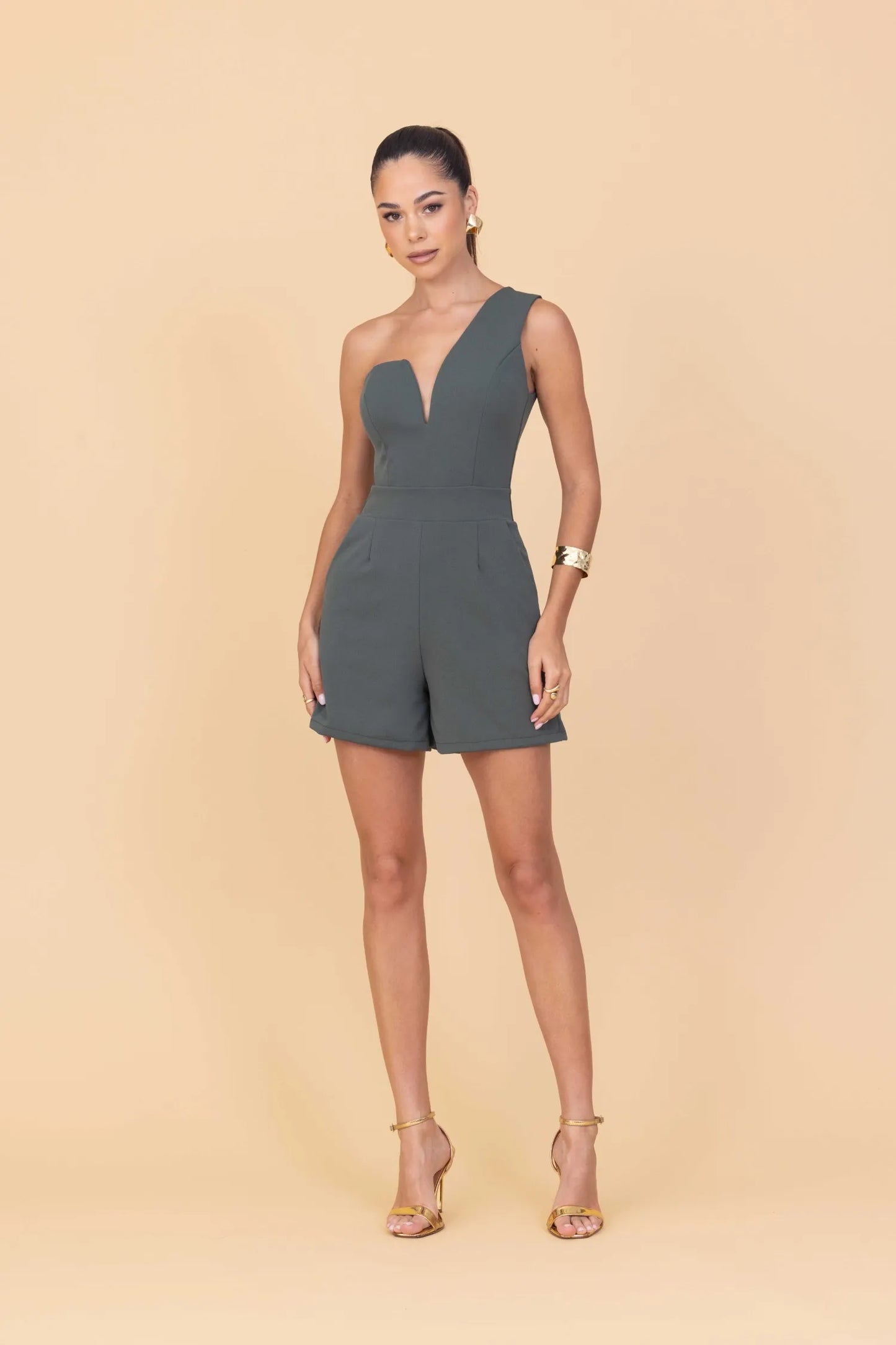 Woman wearing a green romper on a beige background