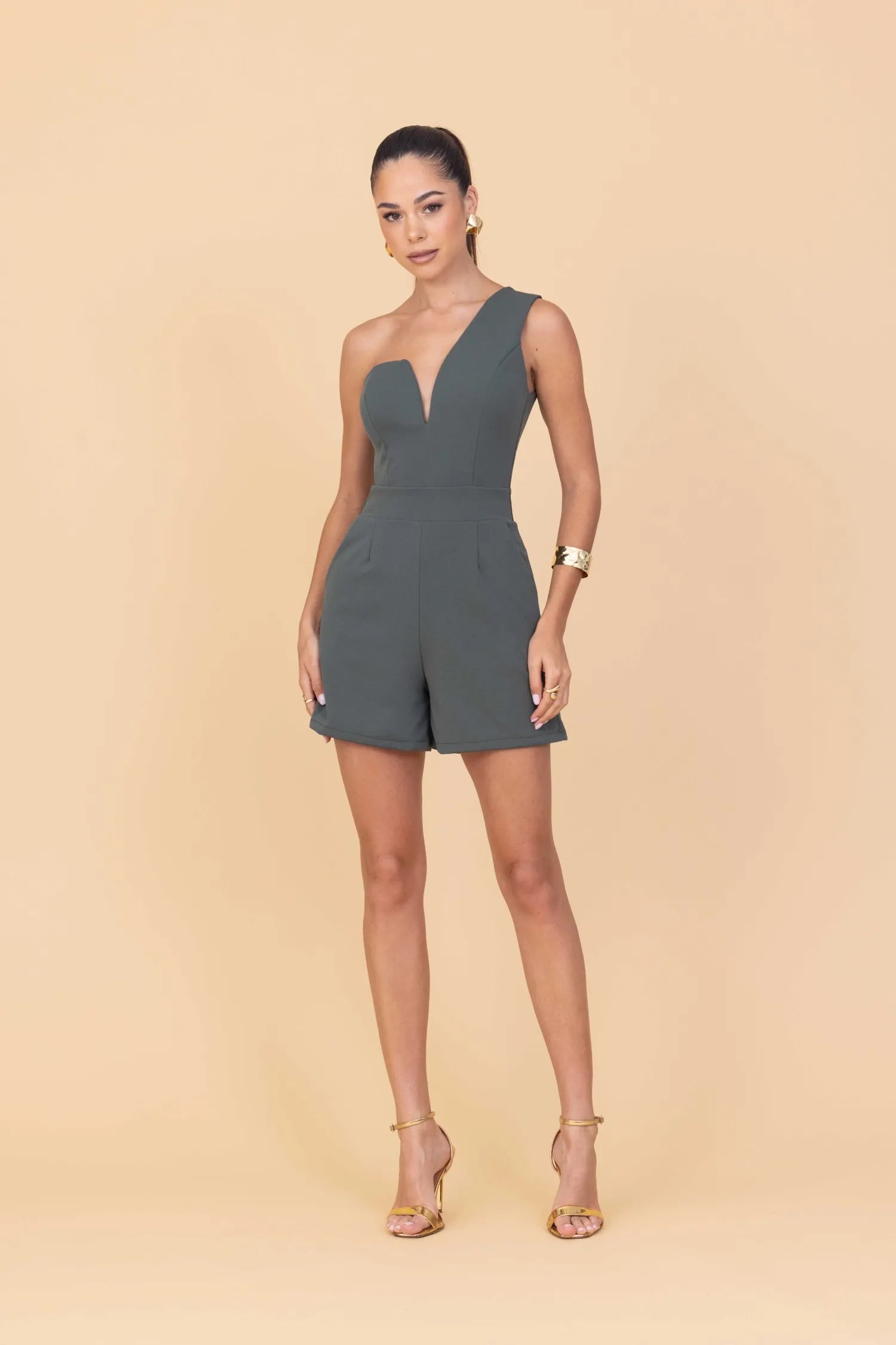 Woman wearing a green romper on a beige background